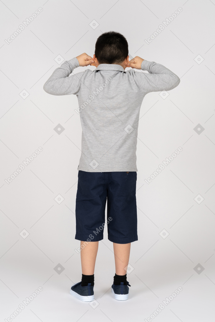 Niño sosteniendo sus orejas