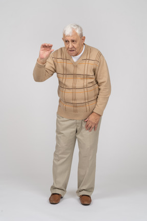 Front view of an old man in casual clothes waving with hand