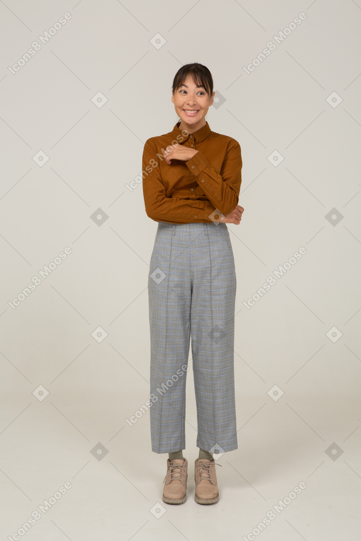Front view of a smiling young asian female in breeches and blouse touching stomach