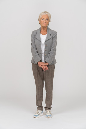 Vista frontal de una anciana en traje mirando a la cámara