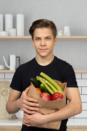 A man holding a paper bag full of vegetables