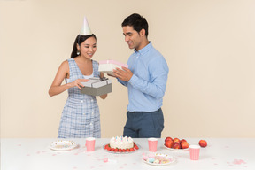 Young asian woman giving present to caucasian man