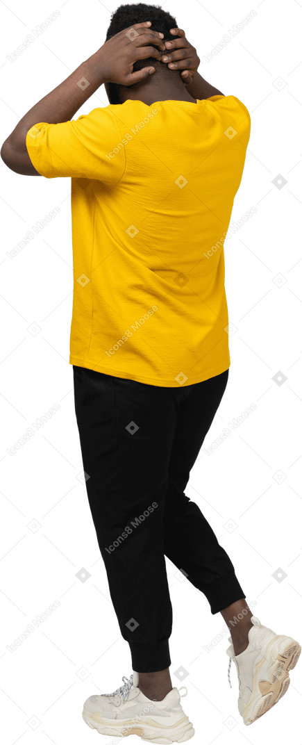 Vista traseira a três quartos de um jovem de pele escura caminhando com uma camiseta amarela tocando a cabeça