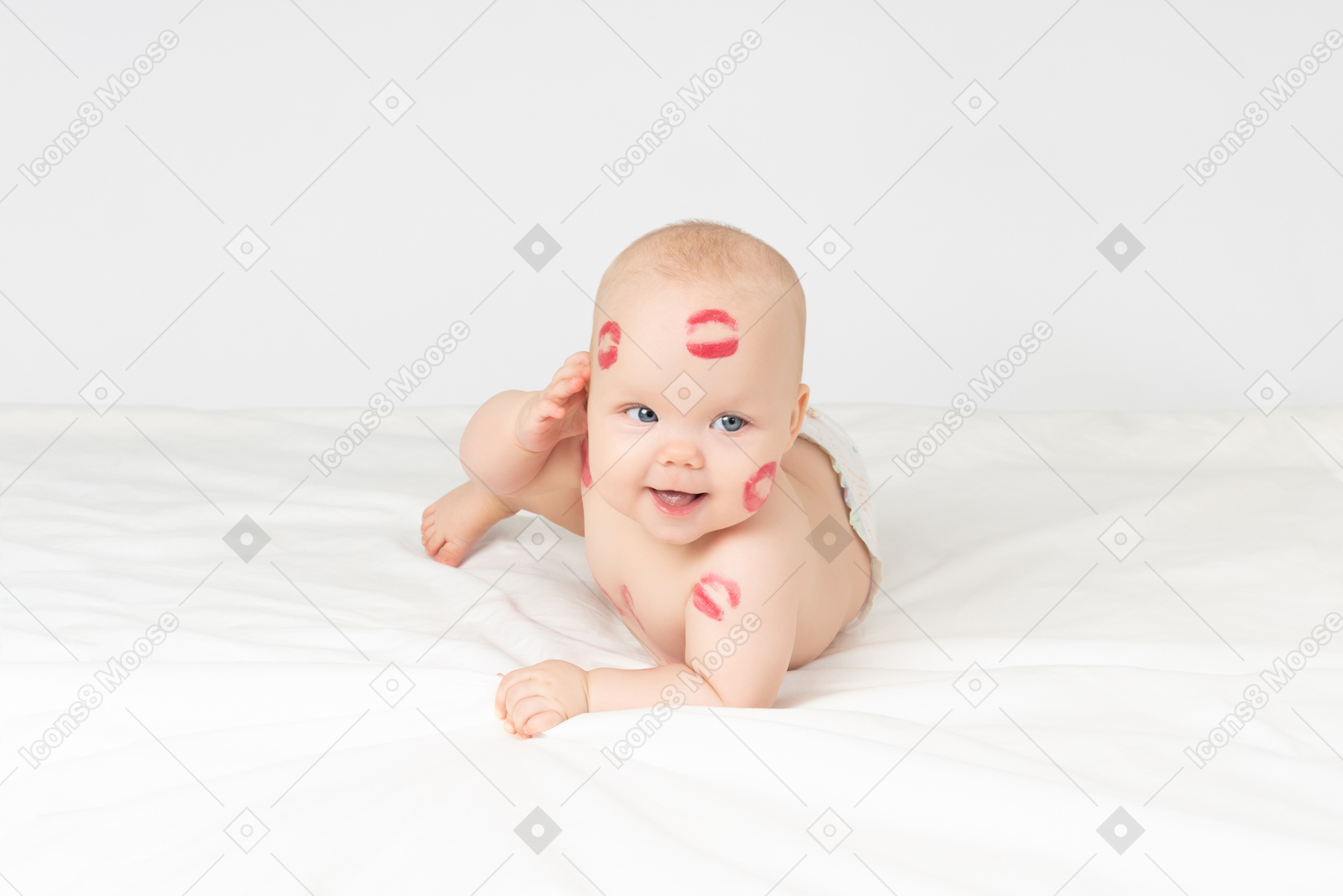 Baby girl with red lipstick kisses lying on the stomach ans touching her face with hand