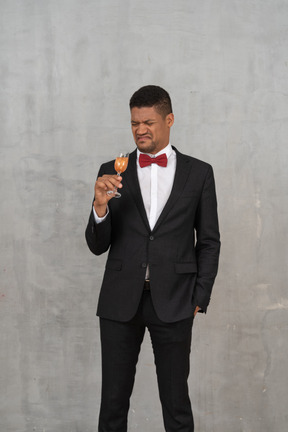 Revolted man in formal wear standing with a glass of champagne