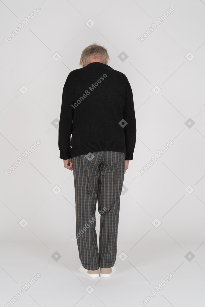 Elderly man standing back to camera and looking down
