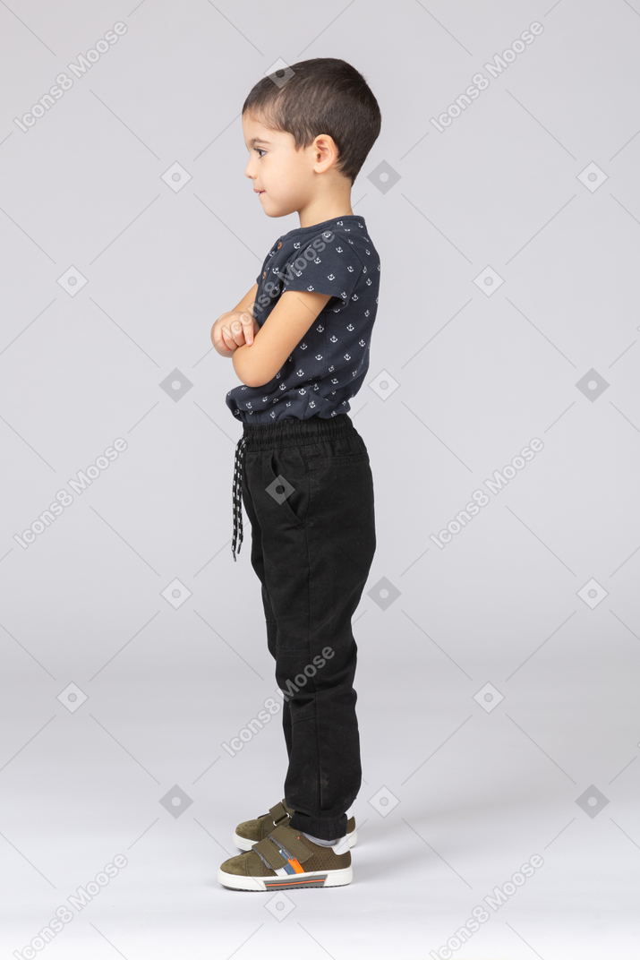 一个可爱的男孩交叉双臂站立的侧视图