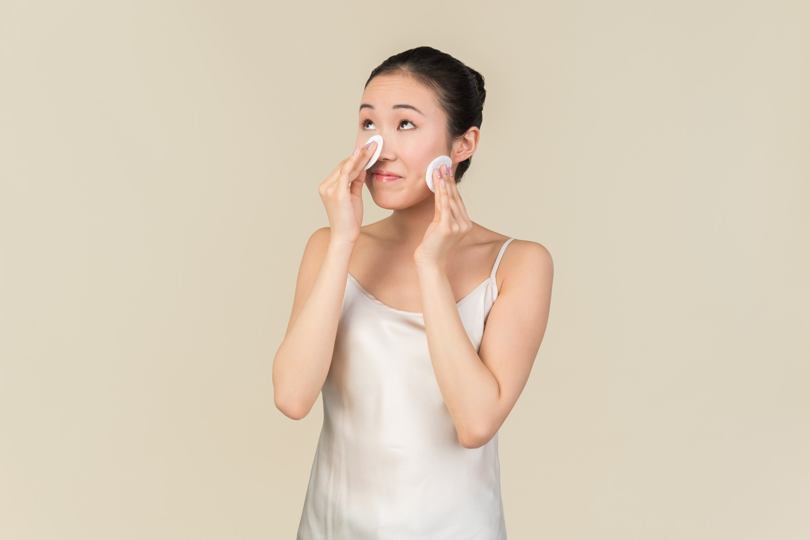 Young asian woman focused on cleaning face with cotton pads