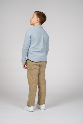 Vista trasera de un niño con ropa informal mirando hacia arriba