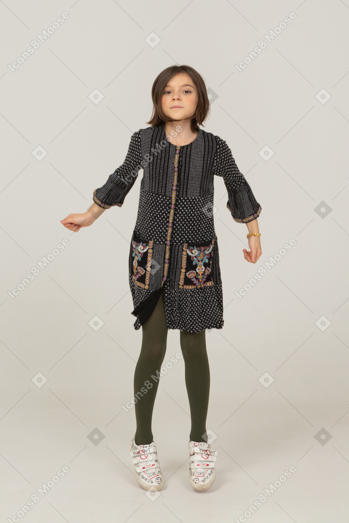 一个跳跃的小女孩的前视图，头发凌乱，穿着裙子