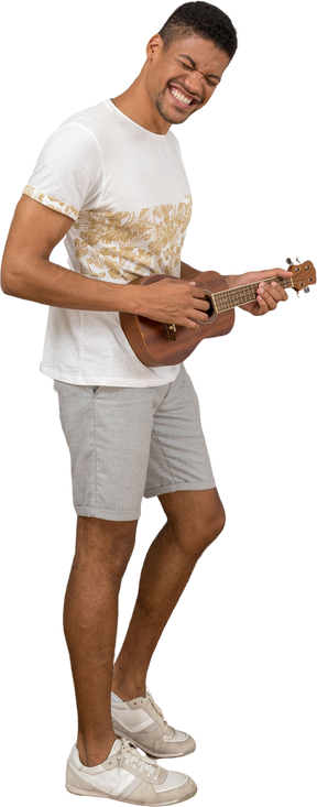 Vista lateral de un hombre tocando el ukelele y sonriendo