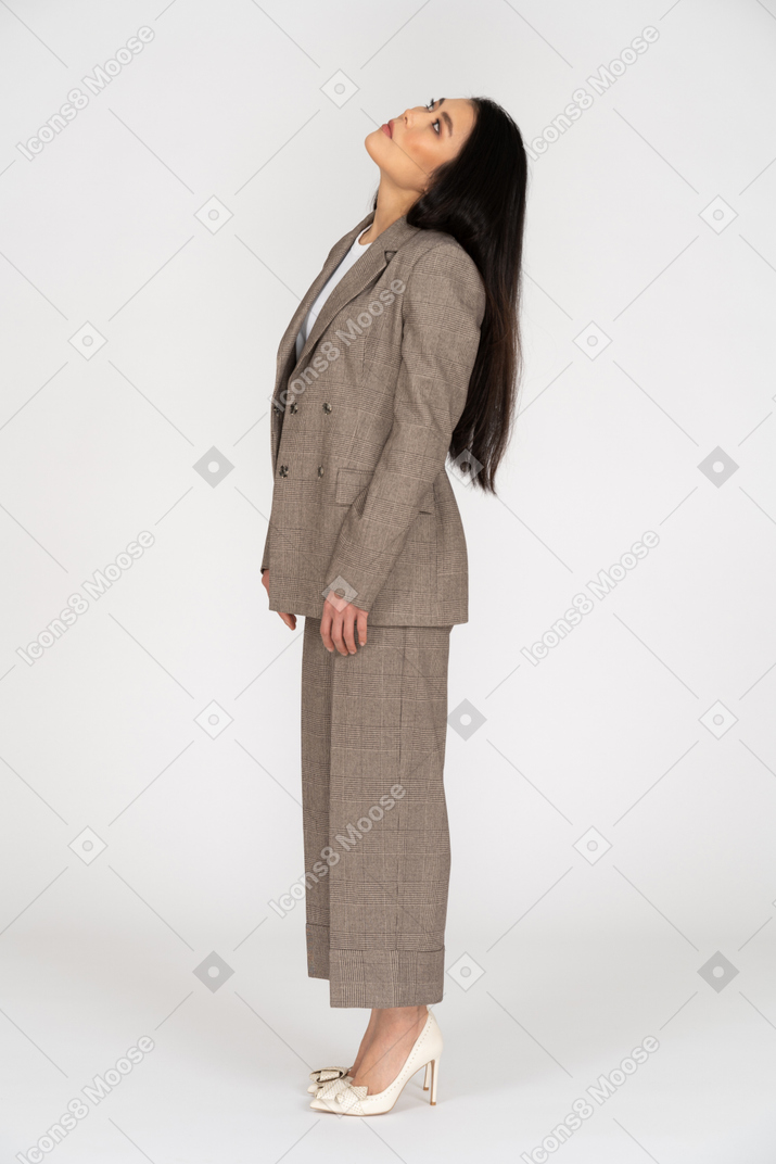 一位年轻的女士，穿着棕色西装，抬头，同时倾斜头的侧视图