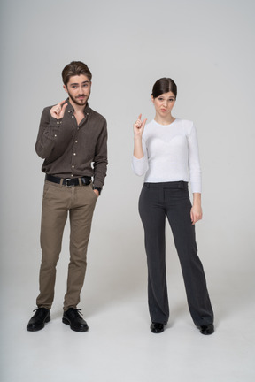 Vista frontal de una joven pareja en ropa de oficina que muestra el tamaño de algo