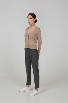 Three-quarter view of a young lady in pullover and pants showing tongue