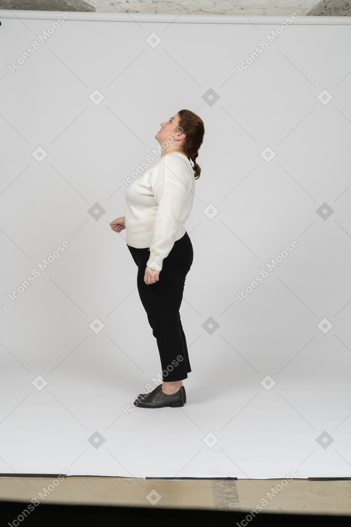 Vista laterale di una donna grassoccia in abiti casual che guarda in alto