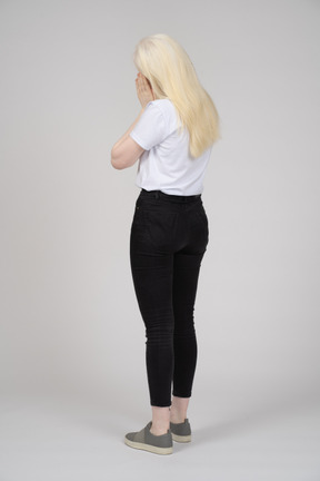 Back view of a blonde woman covering her face