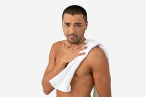 Barechested young male holding a towel on his neck