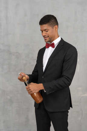 Man in formal wear opening a liquor bottle