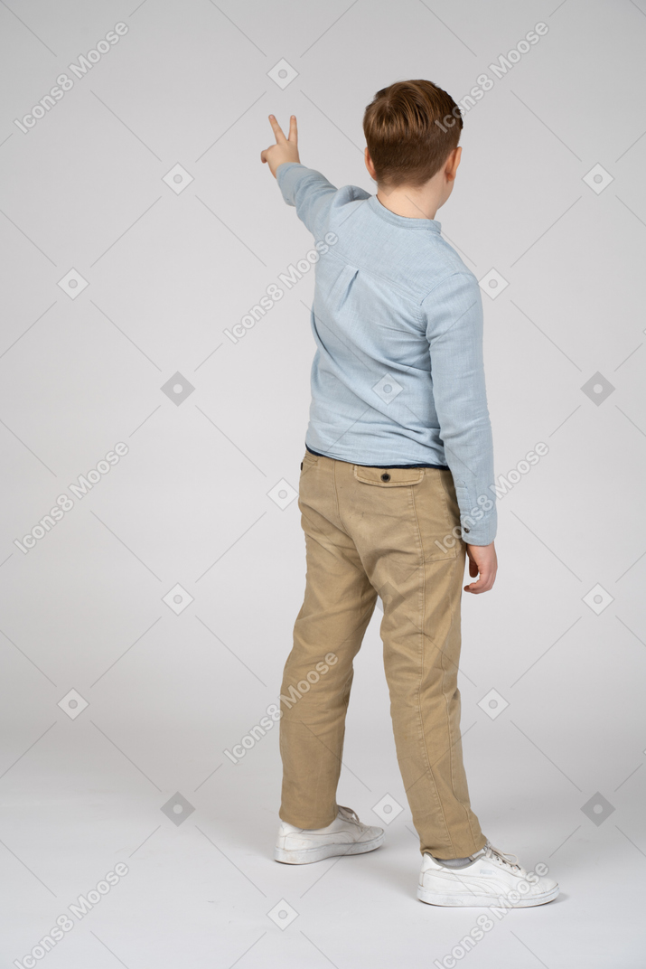 Vista traseira de um menino mostrando sinal de v