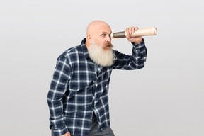 Homme barbu, regardant à travers un tube de papier