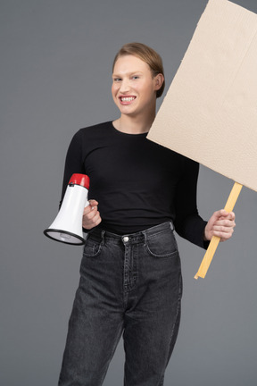 Person smiling with megaphone and sign in hand