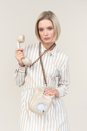 Serious looking young woman holding phone cord over the neck