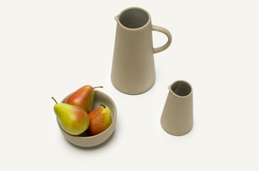 Bowl with pears and some grey jars on a white background