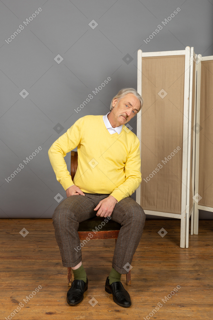 Mann mittleren alters, der mit geneigtem kopf sitzt