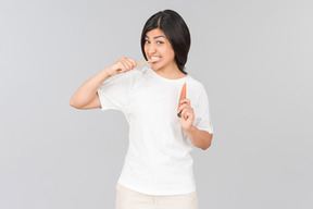 Young indian woman brushing her teeth and holding toothpaste