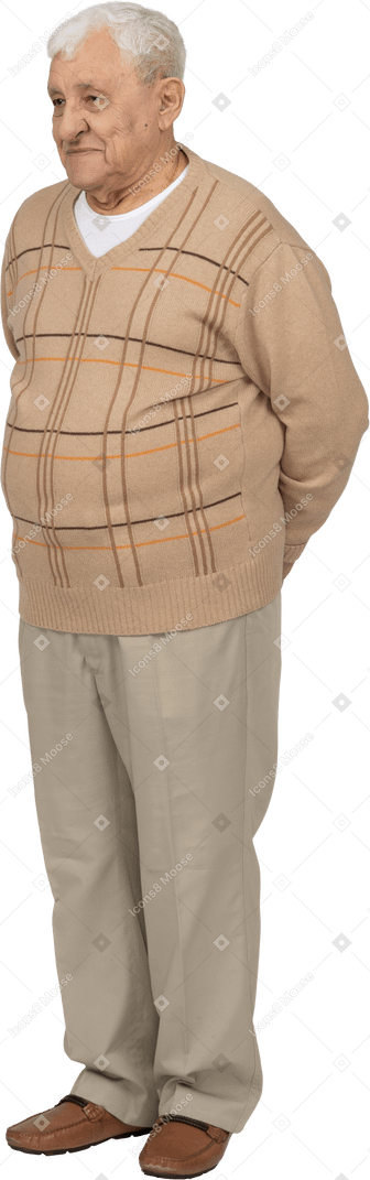 Vorderansicht eines glücklichen alten mannes in freizeitkleidung, der mit den händen hinter dem rücken steht