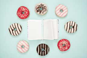 Bunte donuts und ein notizbuch mit einem stift glasieren