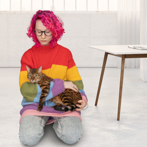 A woman sitting on the floor holding a cat
