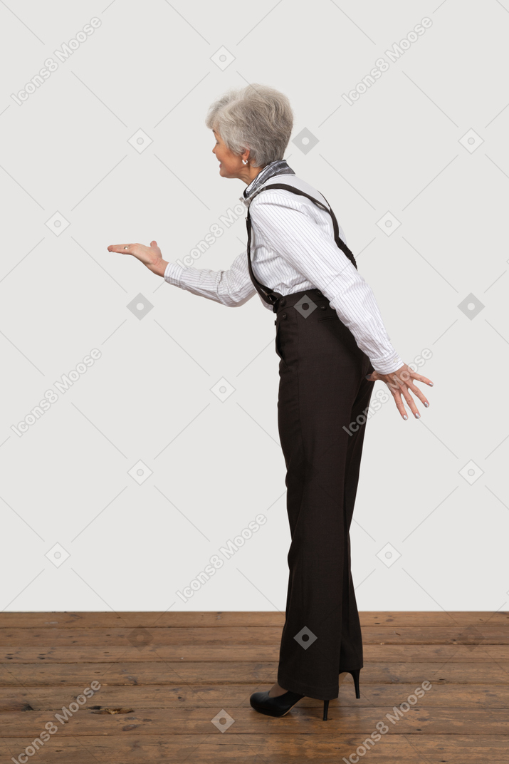 Вид сбоку на старуху в офисной одежде, протягивающую руку