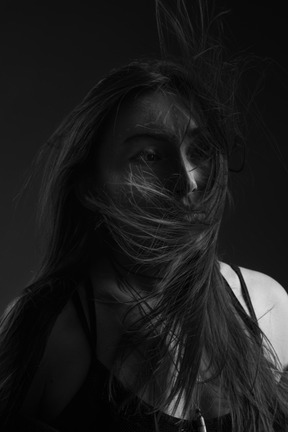 Close-up silueta oscura de una mujer joven con arte facial y cabello desordenado mirando a un lado