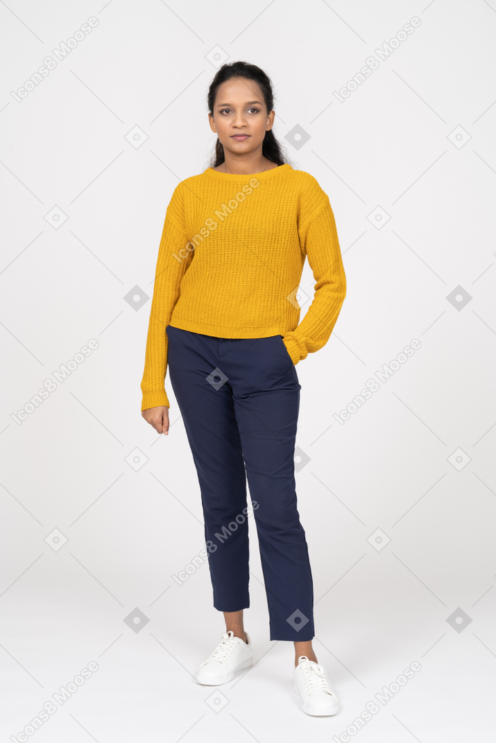 Front view of a girl in casual clothes posing with hand in pocket and looking at camera