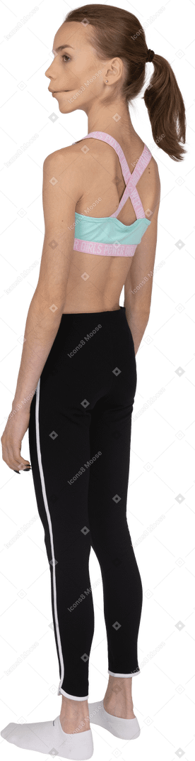 Vista posterior de tres cuartos de una jovencita en ropa deportiva haciendo muecas y mirando a un lado