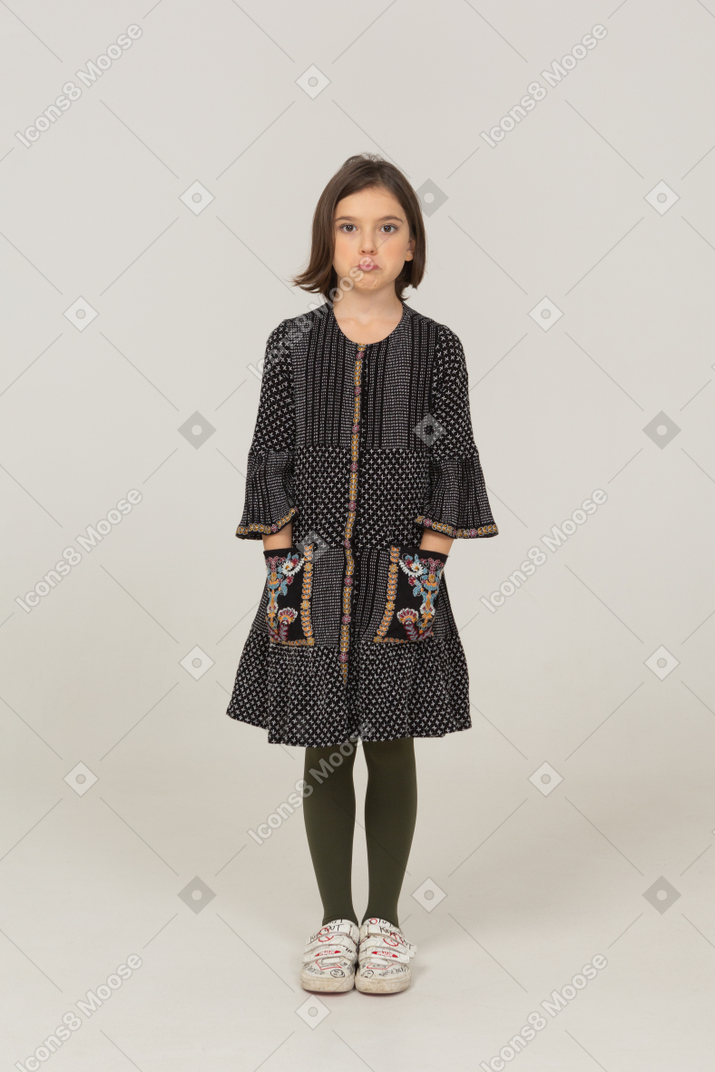 Front view of a pouting little girl in dress putting hands in pockets