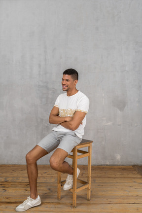 Hombre sonriente sentado en una silla con los brazos cruzados