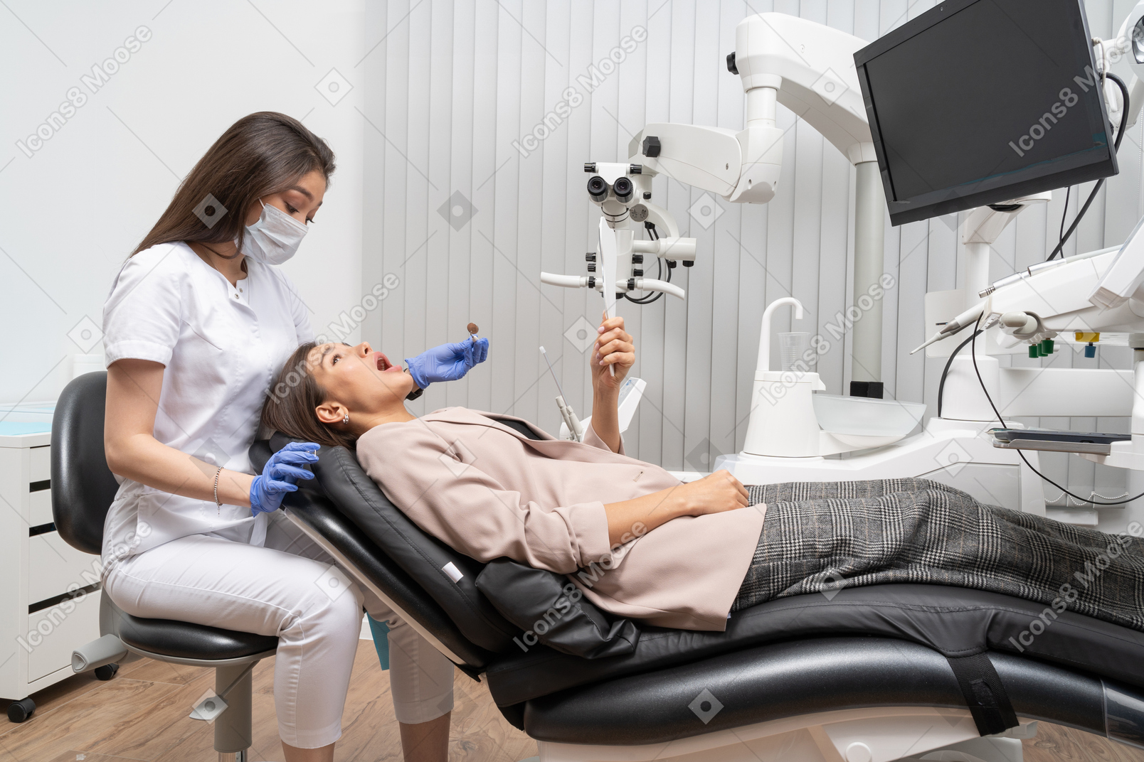 A figura intera di un dentista femminile che esamina il suo paziente con uno specchio