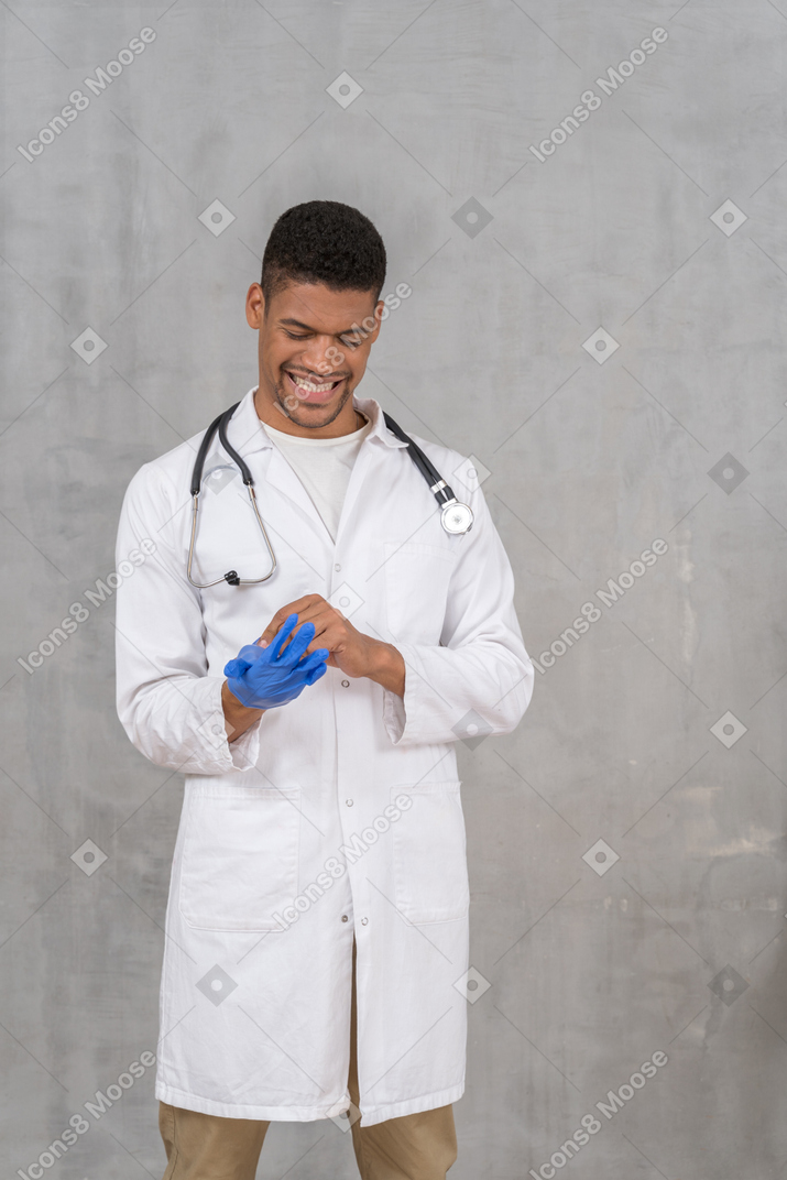 Young doctor taking off nitrile gloves