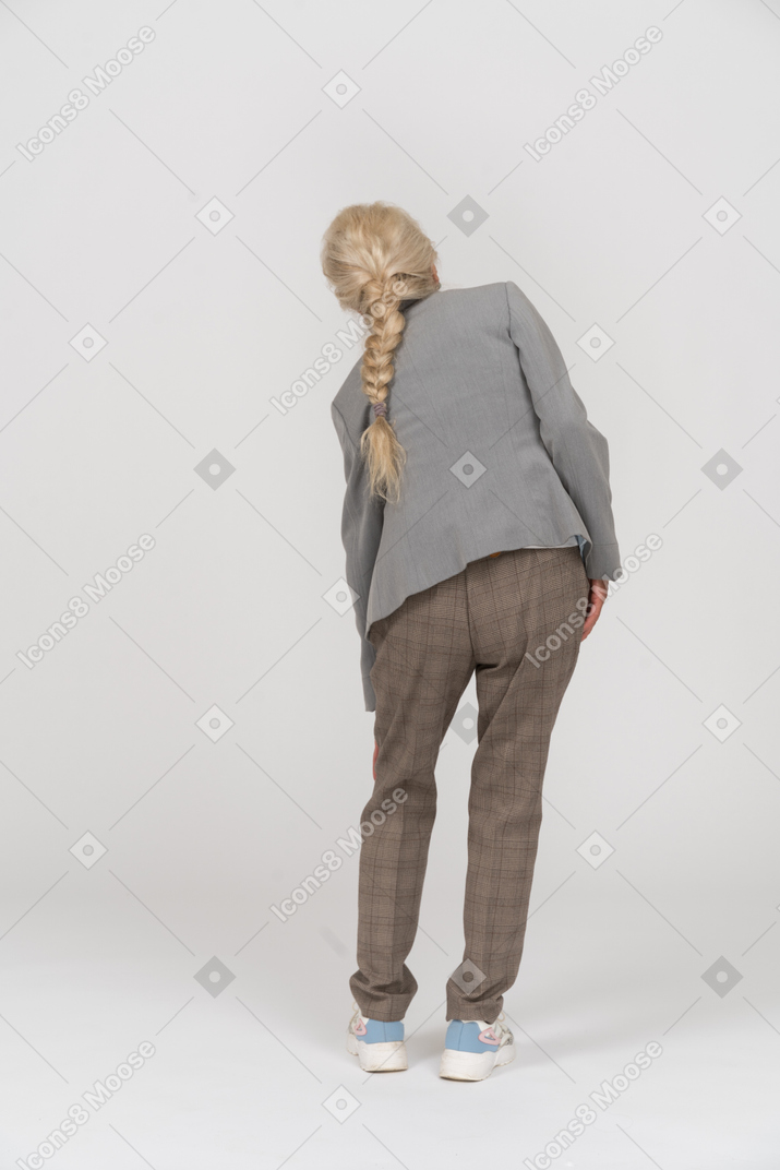 Вид сзади пожилой женщины в костюме, касающейся ее колена