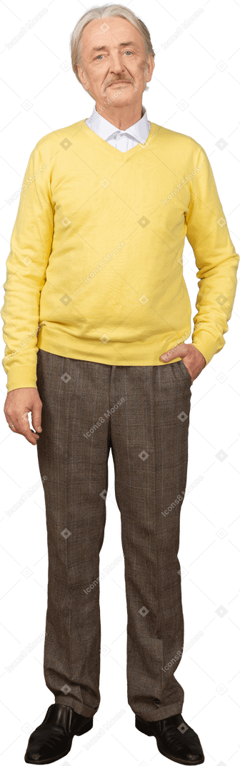 一个不高兴的老人，穿着黄色套头衫，将手放在口袋里，看着相机的前视图