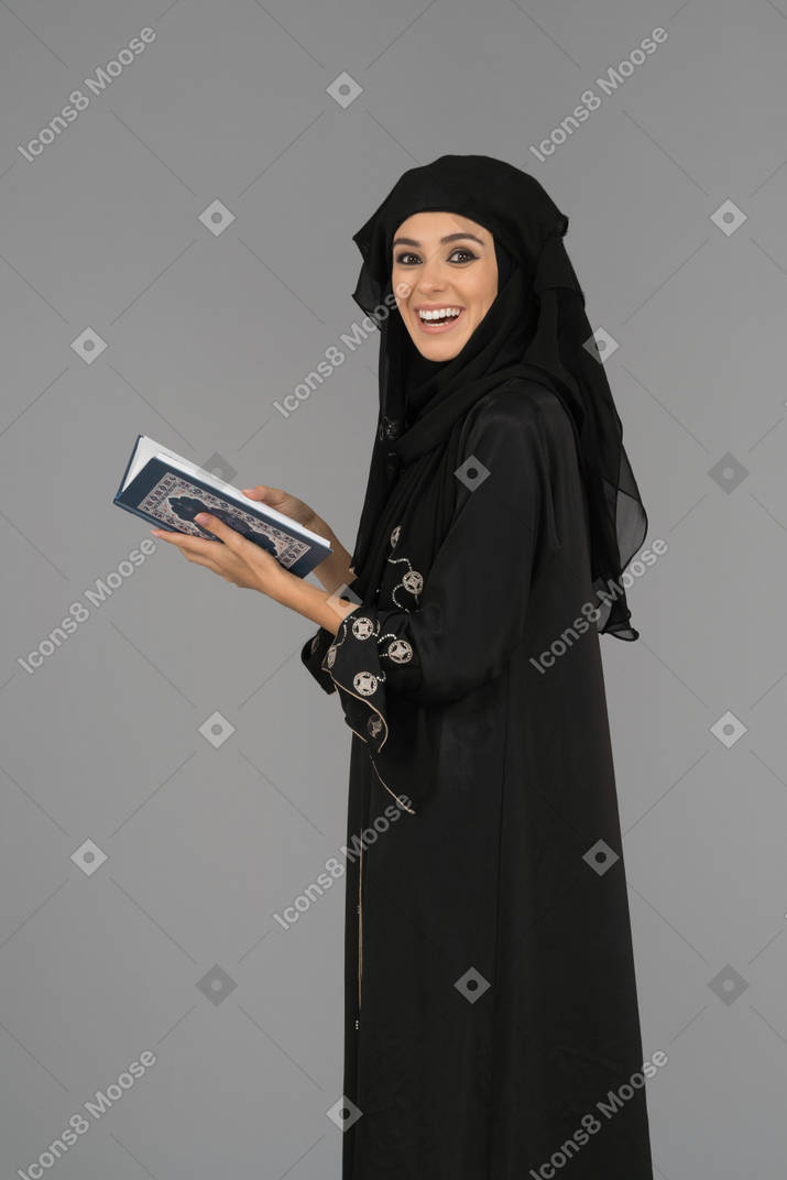 A cheerful muslim woman holding the quran