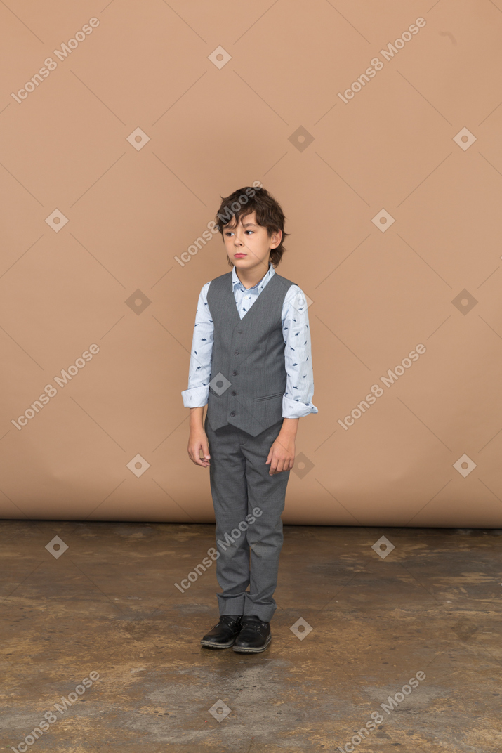 Vista frontale di un ragazzo in abito grigio in piedi immobile