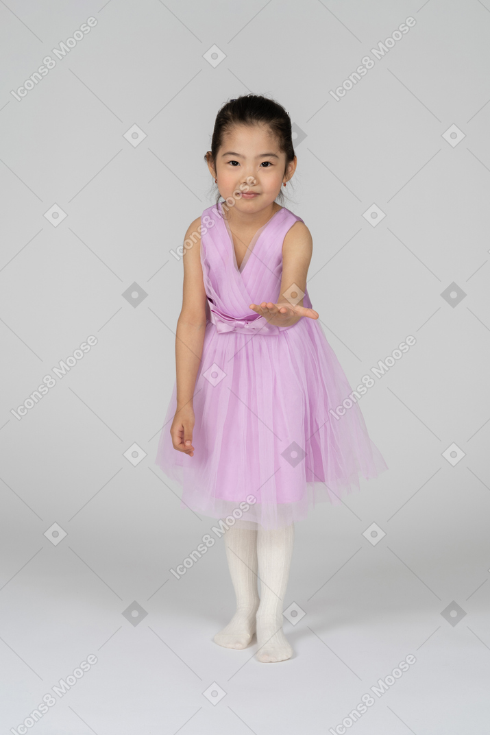 Portrait of a little girl in a tutu dress reaching out her left arm