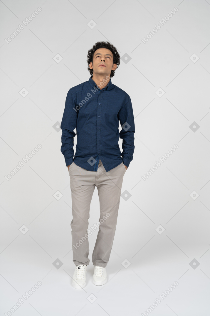 Vista frontal de um homem com roupas casuais em pé com as mãos nos bolsos