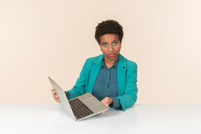 Serious young female office worker holding laptop