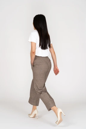 Vista posterior de tres cuartos de una señorita que camina en calzones y camiseta