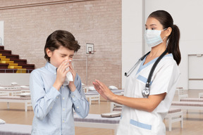 Boy blowing his nose near nurse