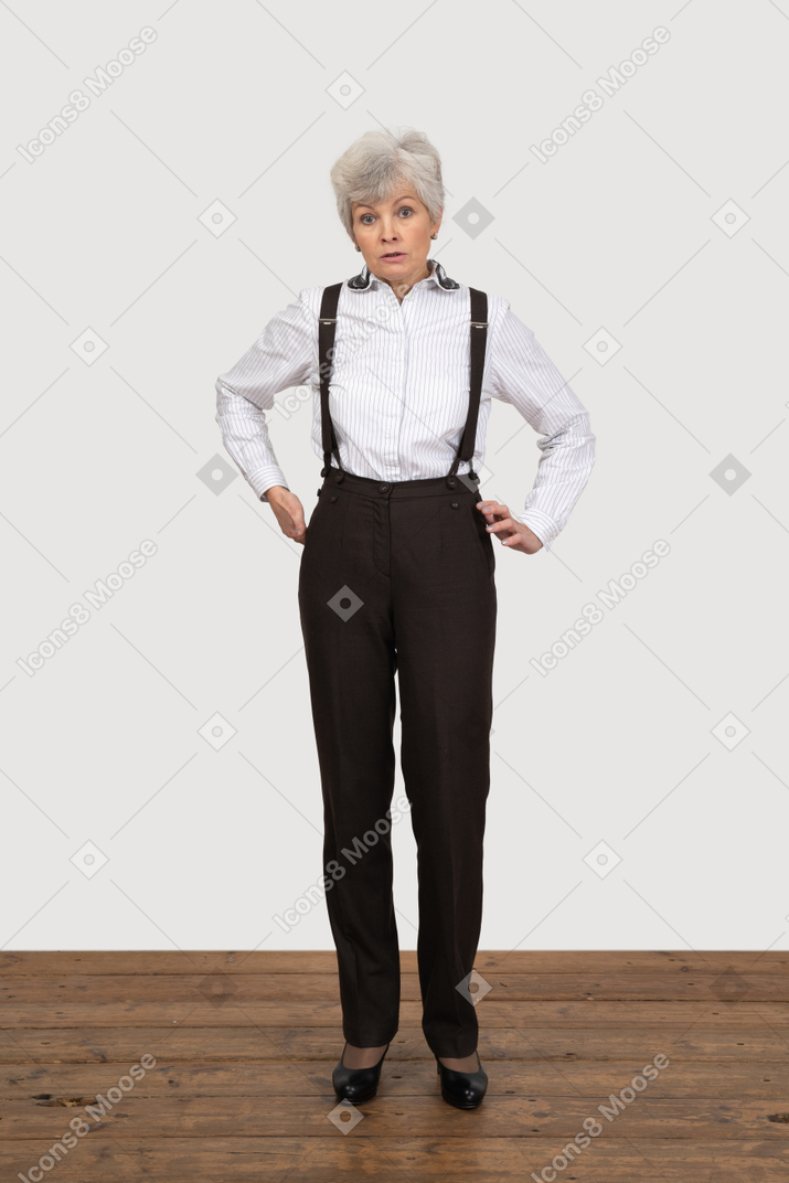 Vista frontale di una vecchia signora scontenta in abiti da ufficio che mette le mani sui fianchi